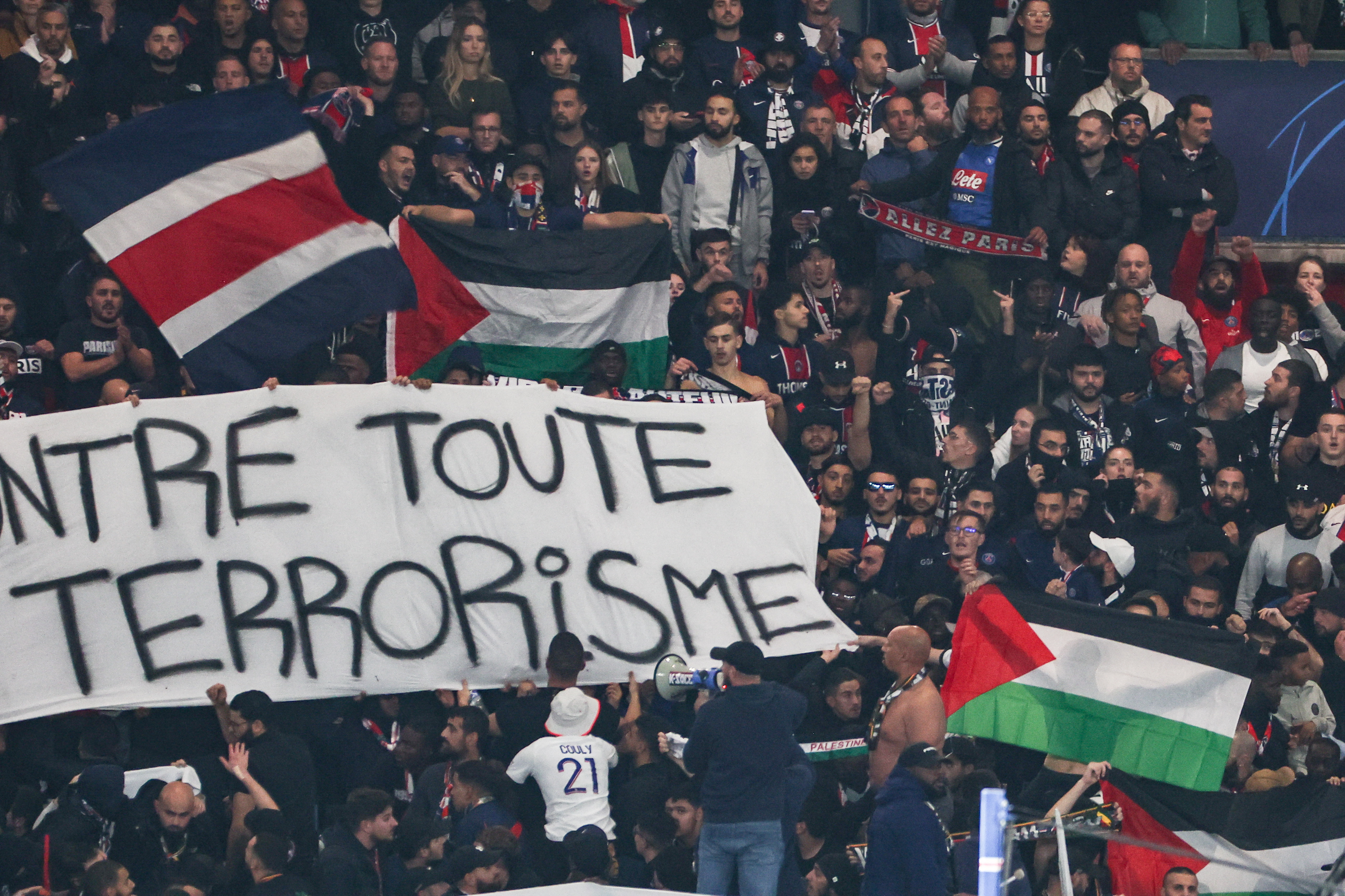 巴黎球迷在看台举巴勒斯坦国旗表支持，并举反对恐怖主义标语